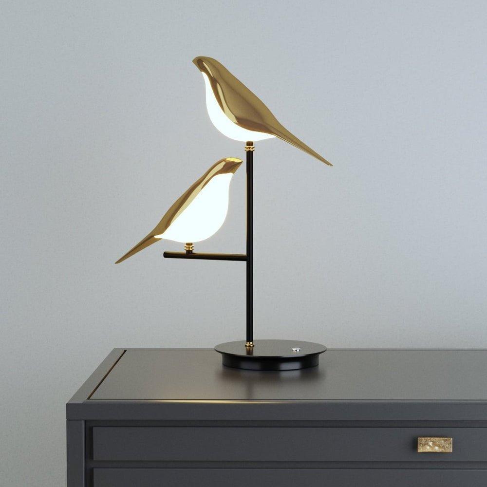 Elegante Tischlampe mit doppelt gestaltetem Vogelmotiv und warmem Licht.