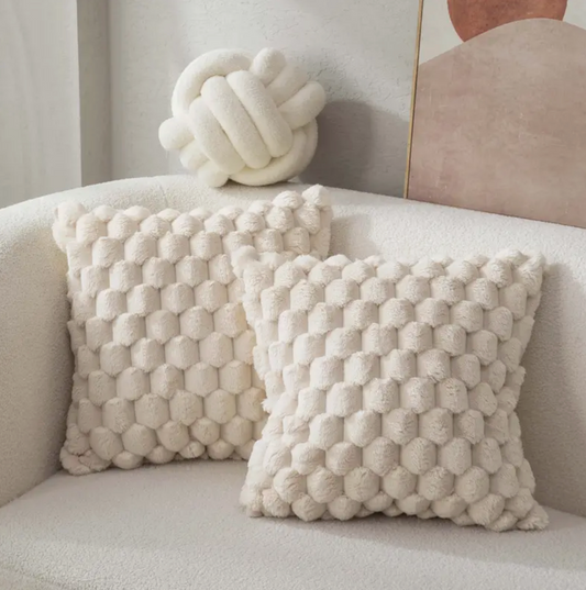 Zwei weiche Dekokissen mit strukturierter Oberfläche auf einem modernen Sofa.