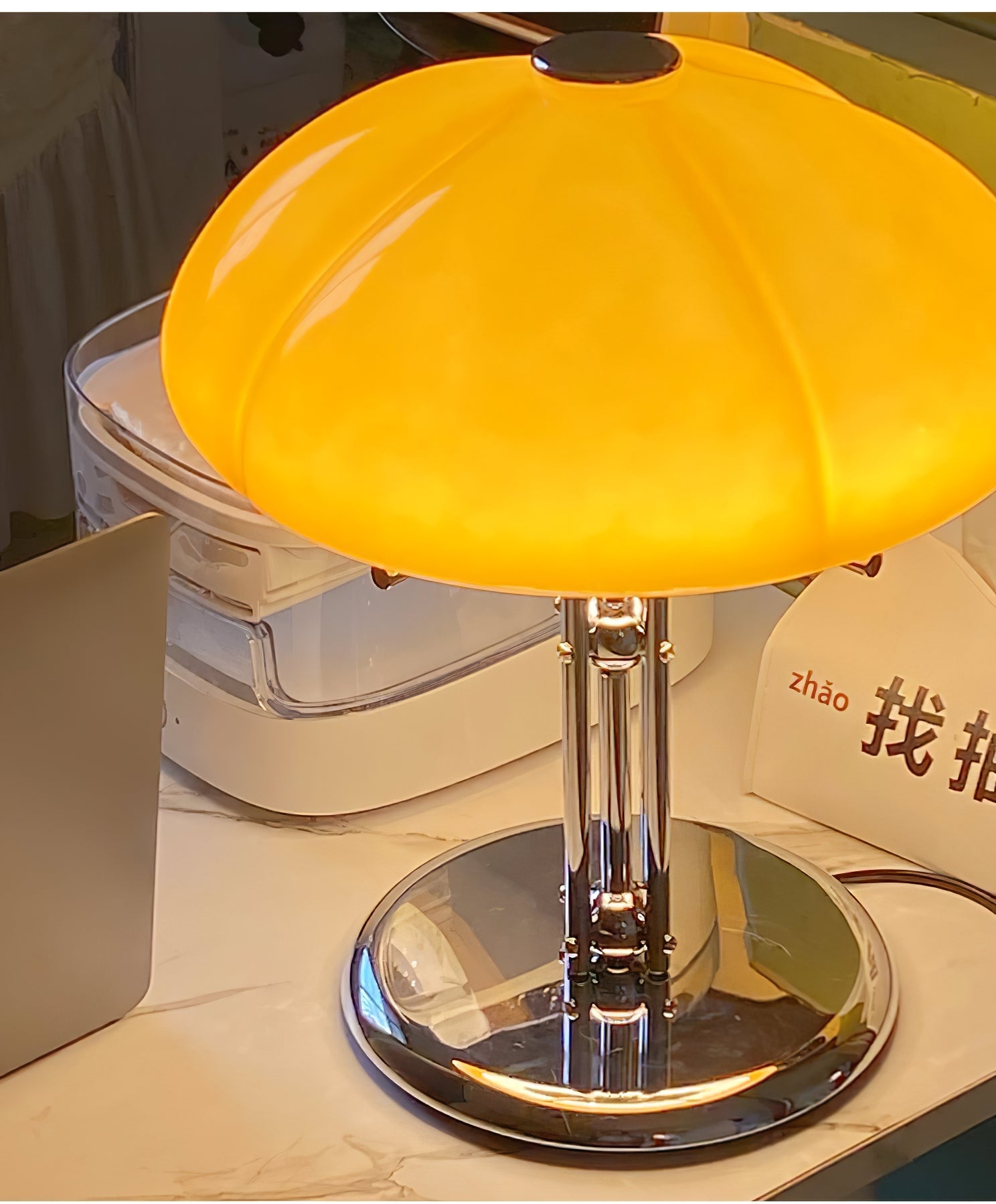Tischleuchte AmberLume mit einem modernen, gläsernen Lampenschirm und Metallfuß.